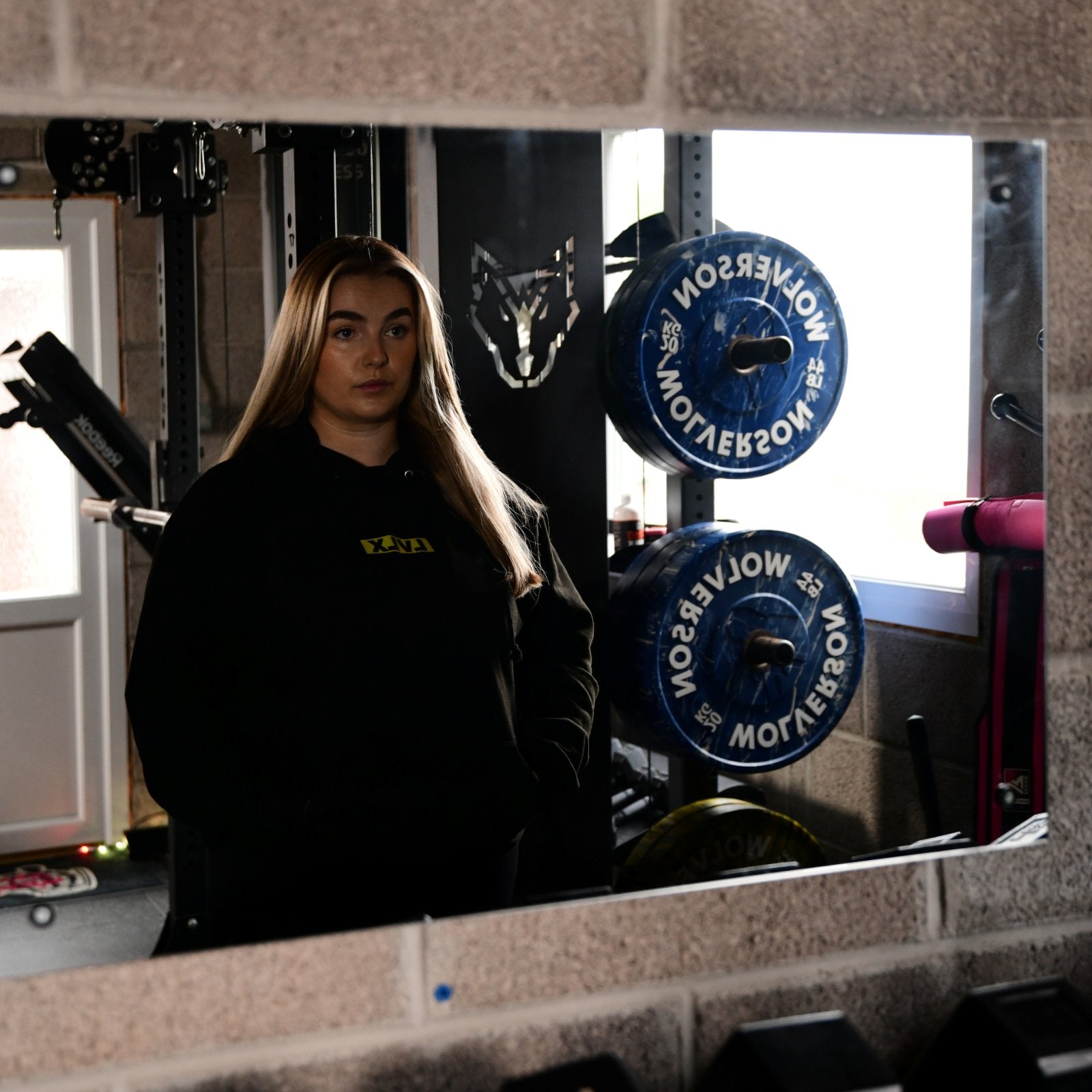 Female model wearing the LVLX hoodie in black, showing relaxed fit and logo on chest